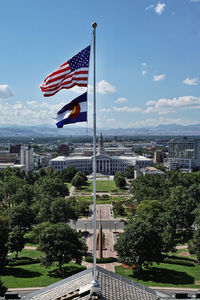 Flag by trees against sky in city