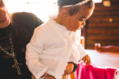 Midsection of mother sitting with daughter at home