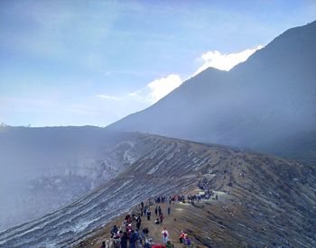 People on mountain against cloudy sky
