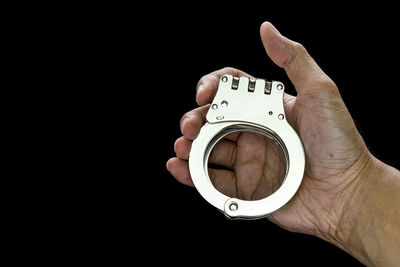 Close-up of hand holding glass over black background