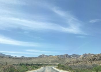Road leading towards mountains against sky