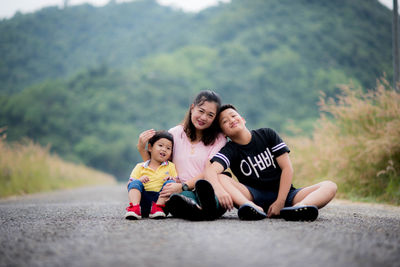 Portrait of mother with kids sitting on road