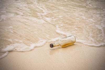 High angle view of bottle on sand at beach