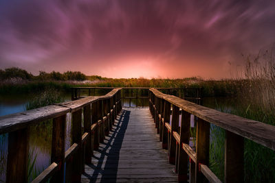 Pier on lake against cloudy sky