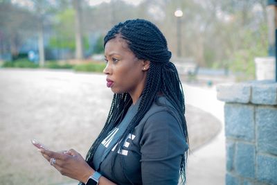 Thoughtful woman using mobile phone in city