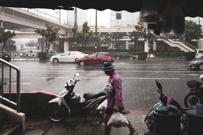 Man riding motorcycle on street in rain
