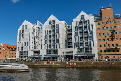 Buildings by river against clear sky