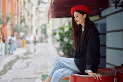 Portrait of young woman sitting in city