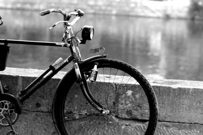 Bicycle parked by railing against lake