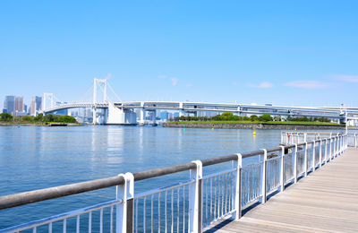 Bridge over calm river against blue sky