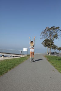 Rear view of woman inline skating on road