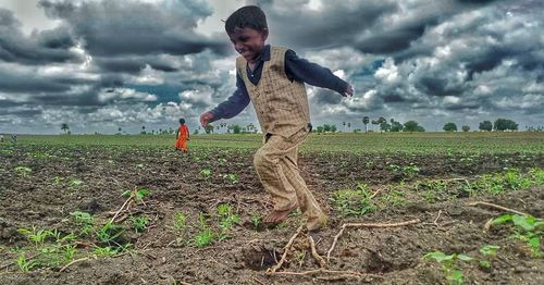 Full length of boy standing on field against sky