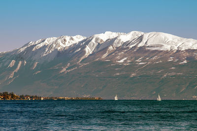 Scenic view of sea and snowcapped mountains against clear sky