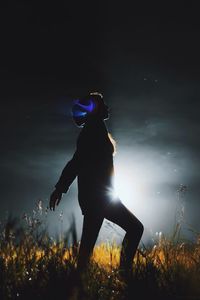 Rear view of woman on field against sky at night