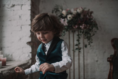 Cute boy standing against wall at home