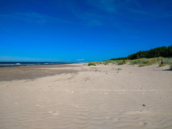 Scenic view of beach against clear blue sky