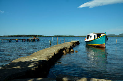 Boats moored in lake against clear blue sky