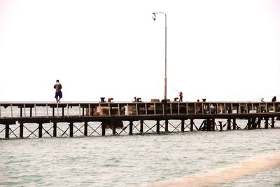 Man standing on bridge over sea against clear sky