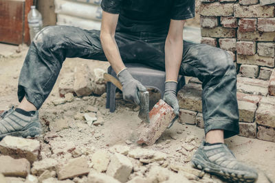 A young man cleans bricks with an axe.