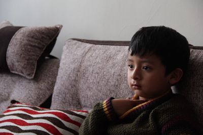 Portrait of boy sitting on sofa at home