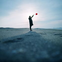 Full length of man releasing balloon on beach