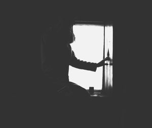 Silhouette woman standing by window at home