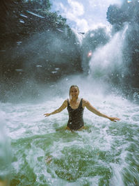 Portrait of woman standing against waterfall