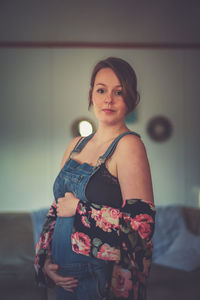 Portrait of young woman standing against wall