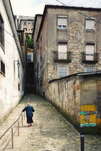 Rear view of person walking on street amidst buildings