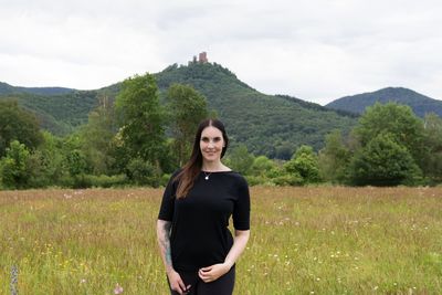 Portrait of smiling young woman standing on field