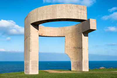 Stone structure by sea against sky