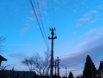 Low angle view of electricity pylon against blue sky