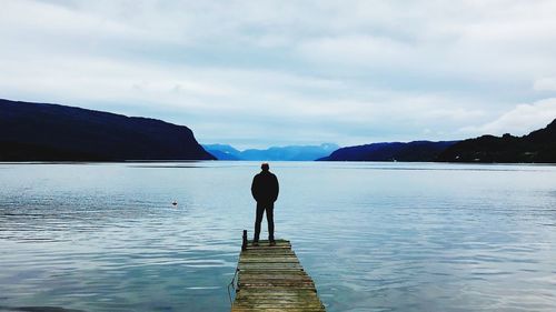 Rear view of man standing on lake against sky