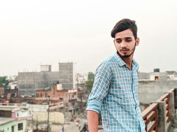 Portrait of young man standing against cityscape