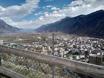 Aerial view of townscape by mountains against sky