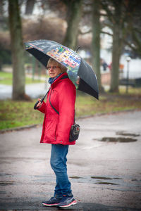 Full length of woman holding umbrella standing on rainy day
