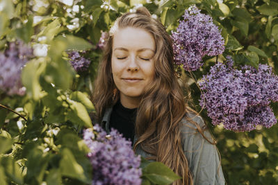 Smiling woman standing against lilac bush