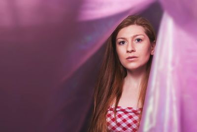 Portrait of beautiful woman seen through curtains