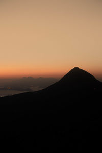 Scenic view of silhouette mountains against orange sky