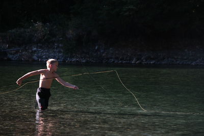 Full length of shirtless man with ball in water