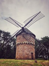 Traditional windmill on field against sky