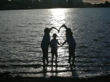 Silhouette friends with reflection in water