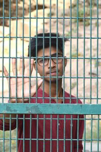 Portrait of teenage boy seen through metal fence