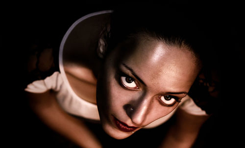 High angle portrait of young woman against black background