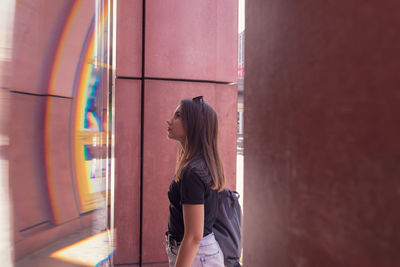 Side view of woman standing against wall