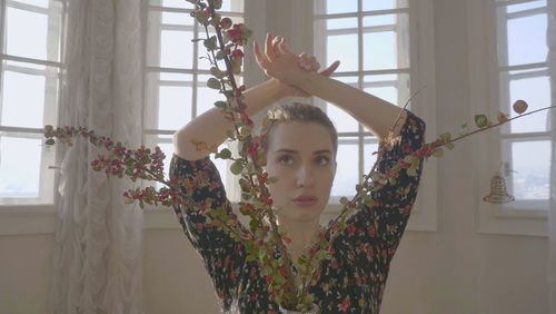 Portrait of young woman standing by window