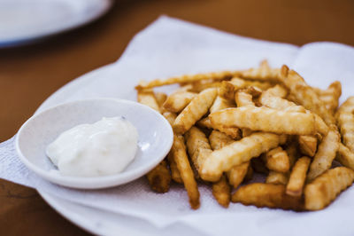 Close-up of french fries with sauce served on table