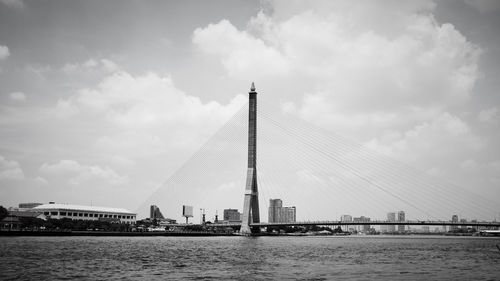 View of bridge over river by buildings against sky