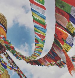 Low angle view of colorful flags hanging against sky