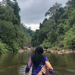 Rear view of women in river against sky while chilling at lata berkelah waterfall, maran, pahang